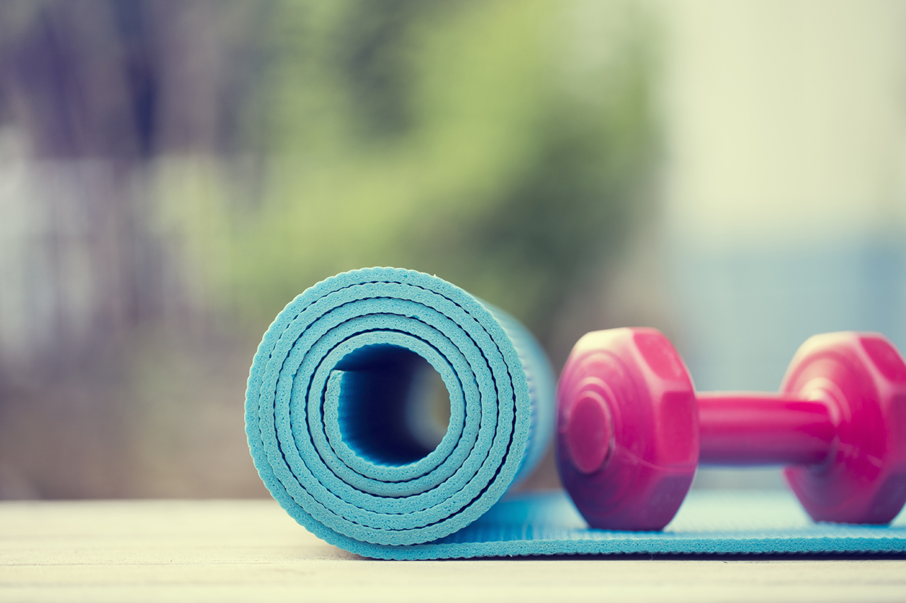 dumbbell and yoga mat on wood table
